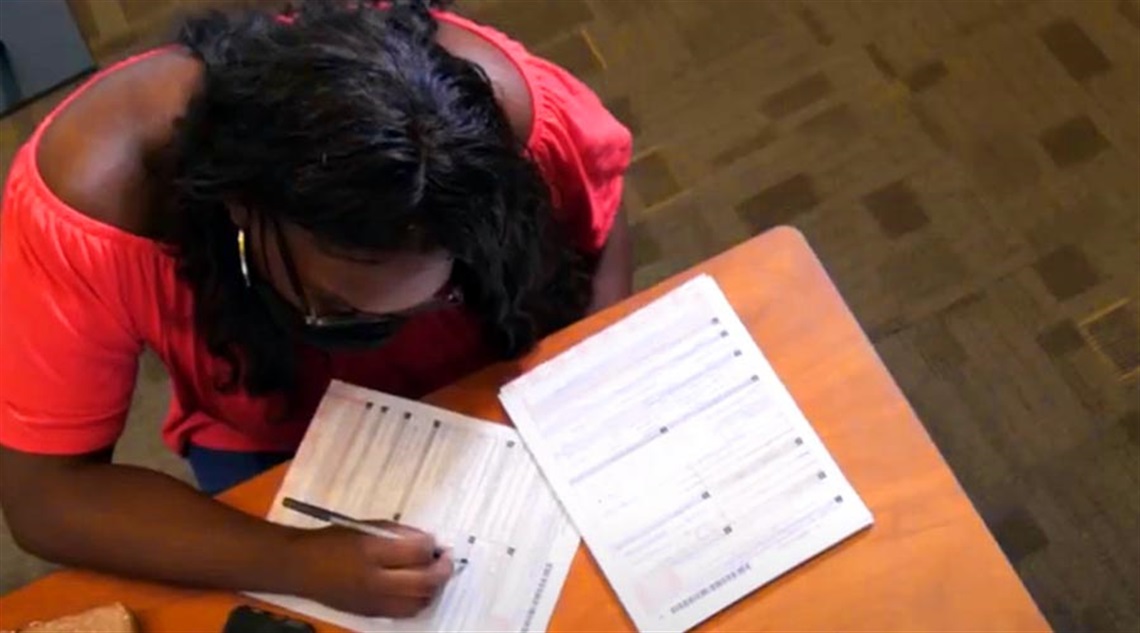 Teen Voter Filling Out a Registration Document in the Precinct