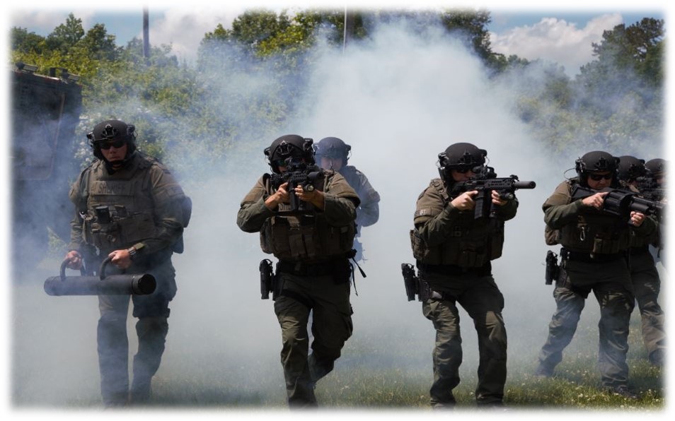 Picture of kitted up deputies coming through smoke guns up.