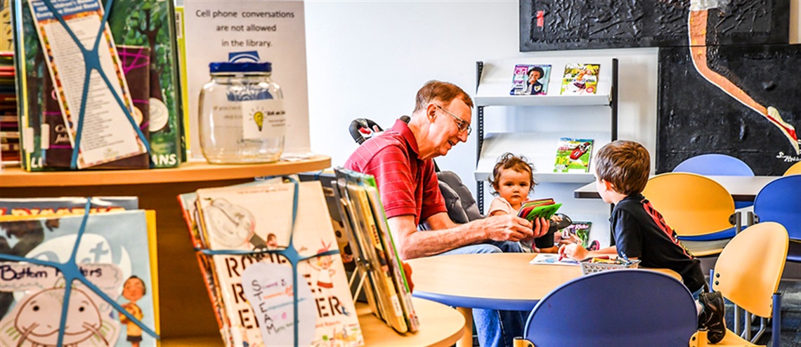 Grandparent Playing a Game with Grandkids at the Library